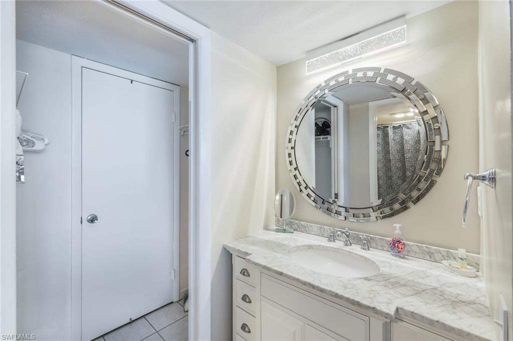 10475 Gulf Shore Drive, Unit 142 Naples, FL 34108 - Photo 11 of 14 a bathroom with a granite countertop vanity a mirror and vanity