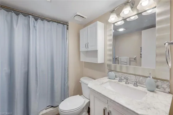 a bathroom with a granite countertop sink toilet a mirror a vanity and shower