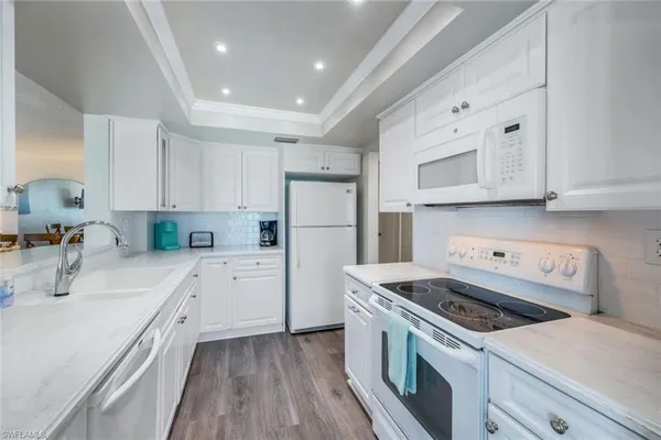 a kitchen with cabinets appliances wooden floor and a window