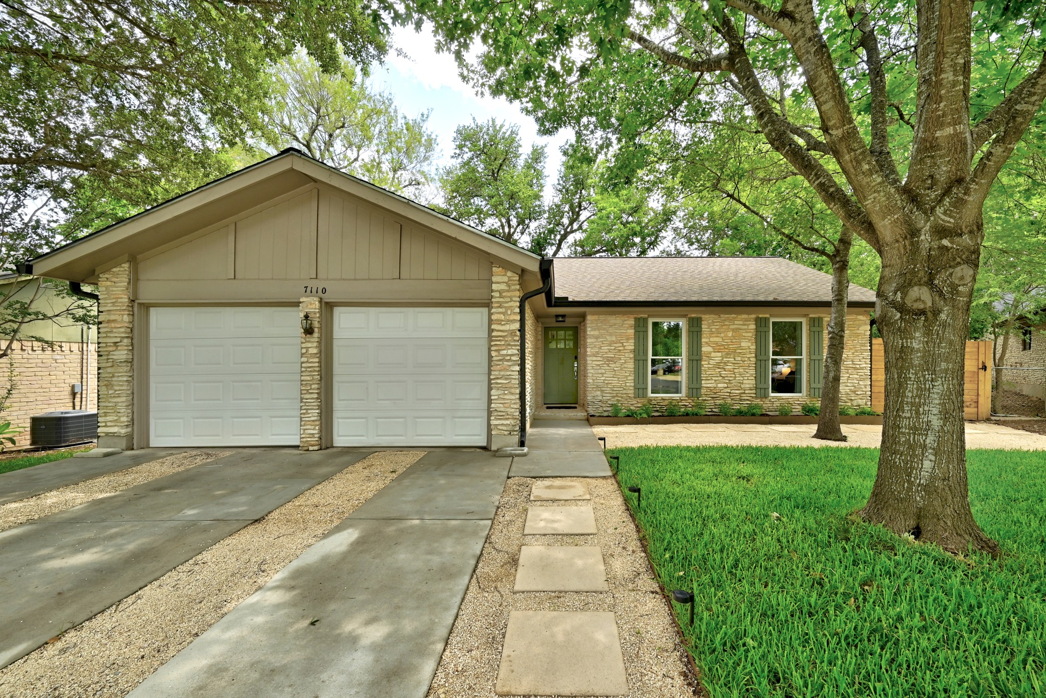 7110 Windrift Way Austin, TX 78745 - Photo 1 of 30 A well-maintained facade features a two-car garage, manicured lawn, and a charming stone walkway.