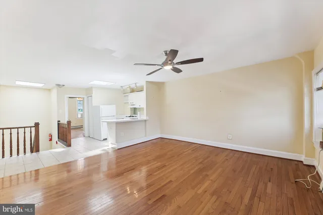 a view of empty room with wooden floor and ceiling fan