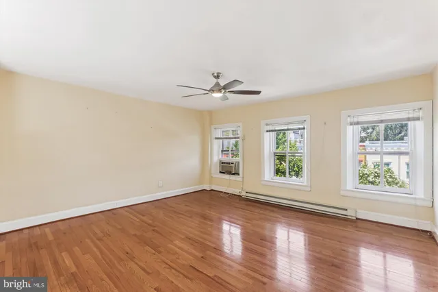 an empty room with wooden floor chandelier and windows