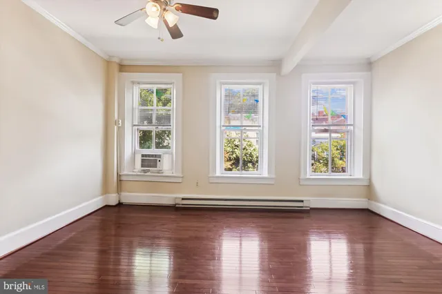 an empty room with wooden floor and windows