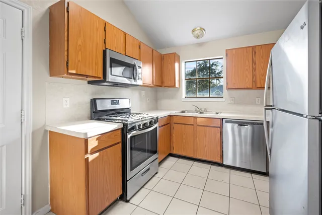 a kitchen with stainless steel appliances granite countertop a stove a sink and a refrigerator