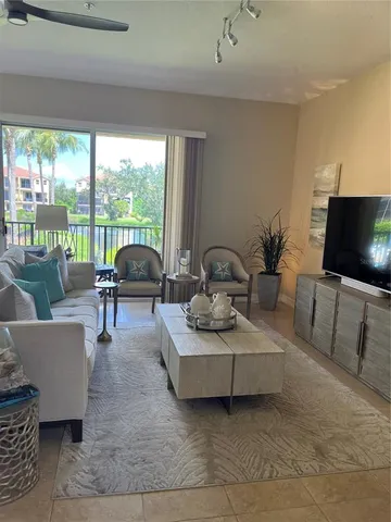 a living room with lots of furniture a chandelier a large window and a rug