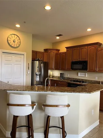 a view of a refrigerator in kitchen and an empty room with wooden floor