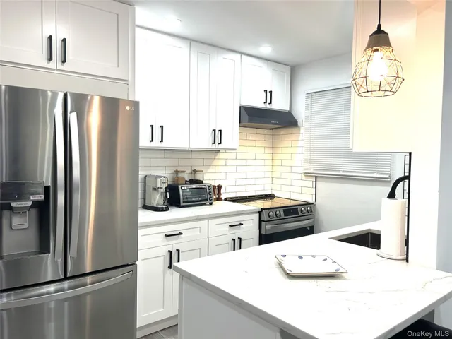 a kitchen with stainless steel appliances a refrigerator a sink a stove a table and chairs