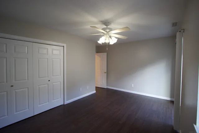 an empty room with wooden floor closet and fan