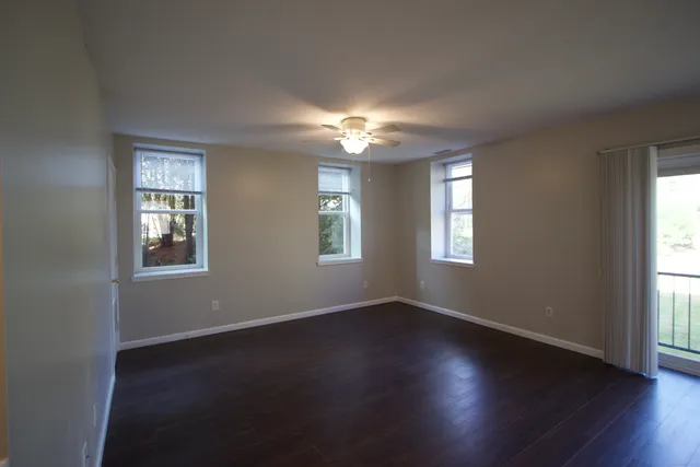 a view of an empty room with wooden floor and a window