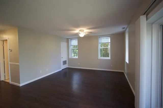 an empty room with wooden floor and windows
