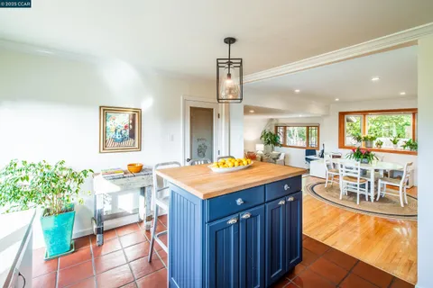 wooden kitchen with stainless steel appliances granite countertop a stove a sink dishwasher and a dining table with garden view