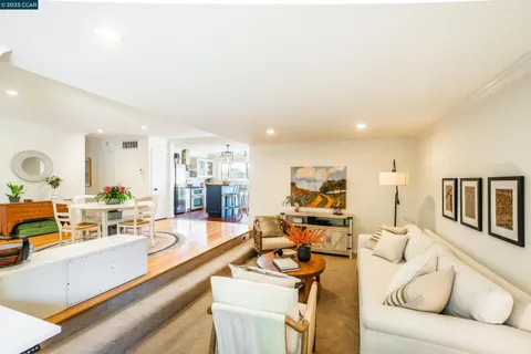 a living room with furniture kitchen view and a large window