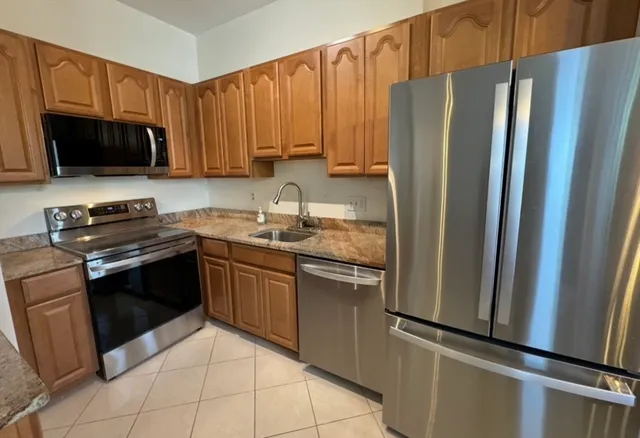 a kitchen with stainless steel appliances granite countertop a refrigerator stove top oven and sink