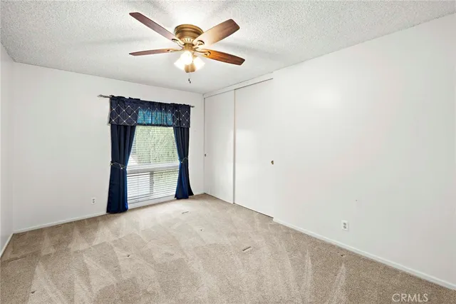 an empty room with a window and a fan