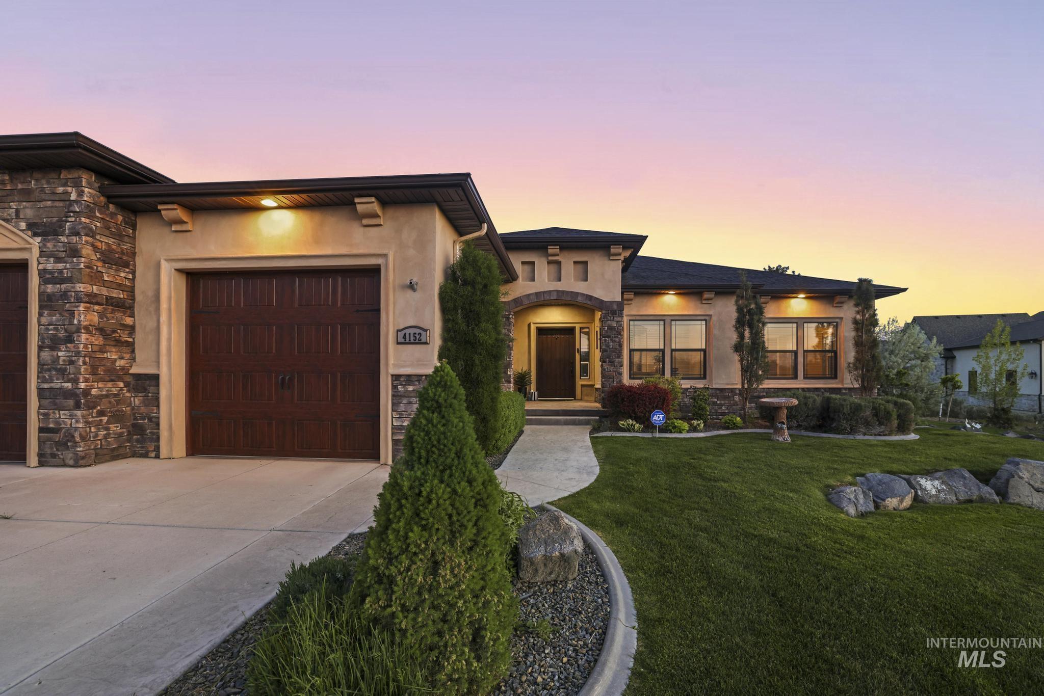 4152 North Meadow Ridge Circle Twin Falls, ID 83301 - Photo 2 of 50 Contemporary exterior featuring a stone and stucco facade, a dark wood-finish garage door, and a curved concrete pathway