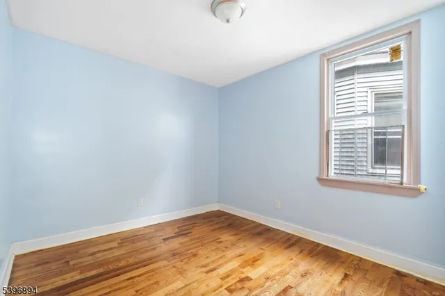 a view of an empty room with wooden floor and closet