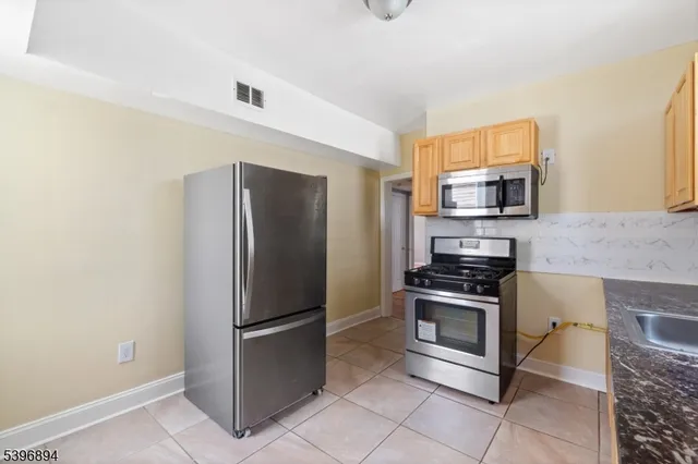 a kitchen with granite countertop white cabinets stainless steel appliances and a sink