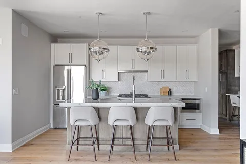 a kitchen with stainless steel appliances a dining table chairs and white cabinets