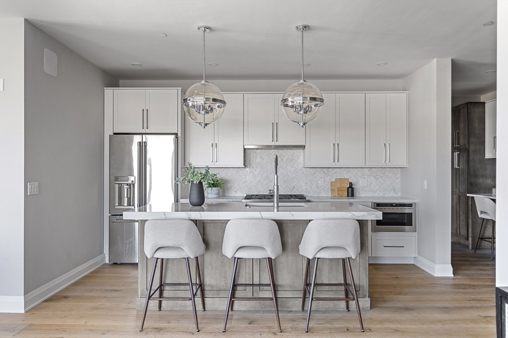 a kitchen with stainless steel appliances a dining table chairs and white cabinets
