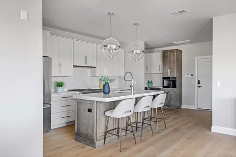 a kitchen with stainless steel appliances a dining table chairs and wooden floor