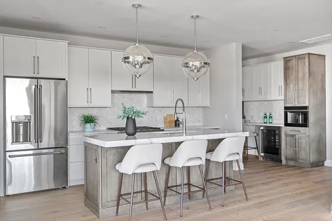 a kitchen with stainless steel appliances a dining table a sink a stove and refrigerator