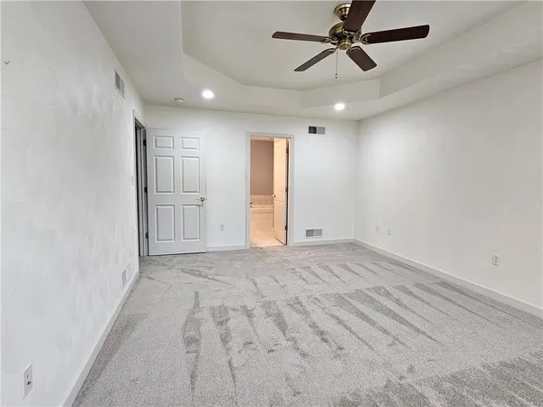 an empty room with chandelier fan and windows