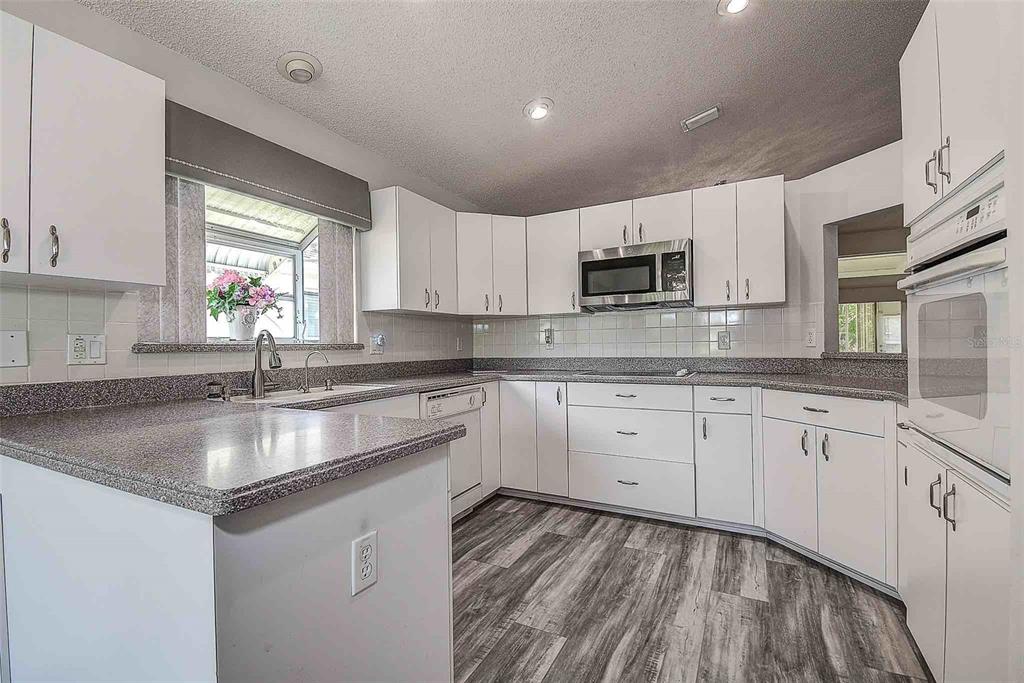 1020 Trafalgar Drive New Port Richey, FL 34655 - Photo 7 of 41 a kitchen with granite countertop a sink stove and cabinets