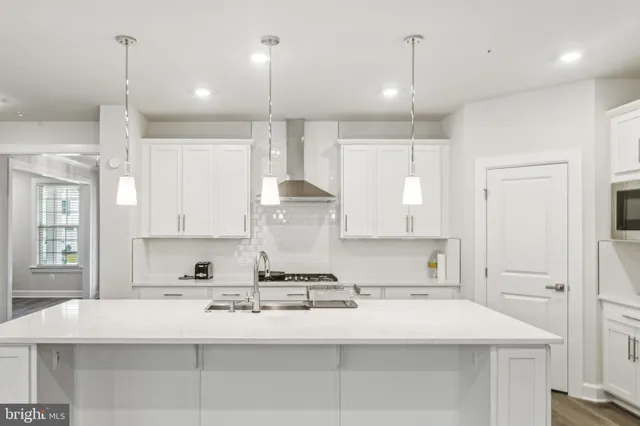a kitchen with kitchen island a counter top space a sink stainless steel appliances and cabinets