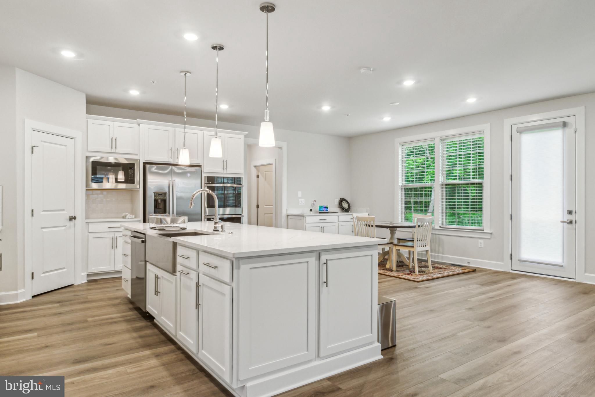 6536 Clubhouse Drive Laurel, MD 20708 - Photo 10 of 40 a kitchen with stainless steel appliances kitchen island a large island in the center and wooden floors