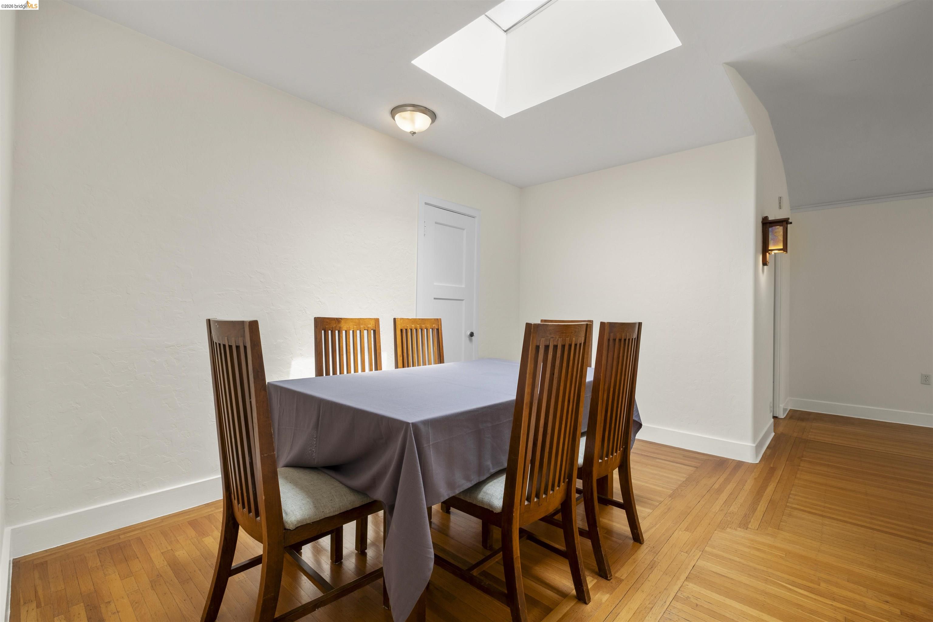 2444 Virginia Street, Unit B Berkeley, CA 94709 - Photo 19 of 39 Dining area featuring a skylight, wood-finish flooring, a flush-mount ceiling light, and white baseboards