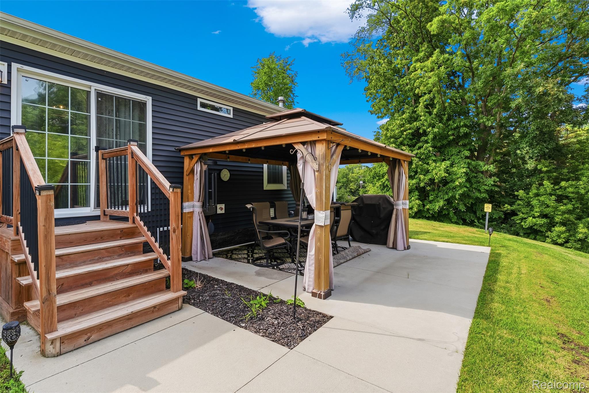 6450 Prince Boulevard Fenton, MI 48430 - Photo 29 of 31 Expansive concrete patio with a built-in gazebo featuring privacy drapes