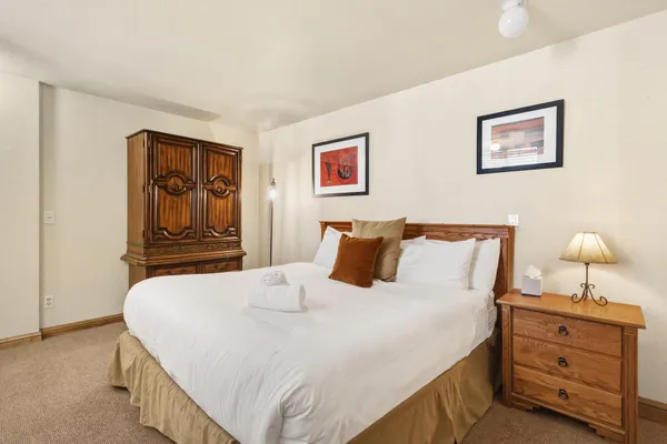 a bedroom with a bed and a lamp on dresser