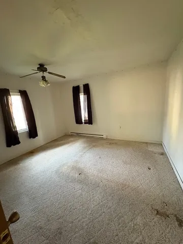 an empty room with windows and ceiling fan