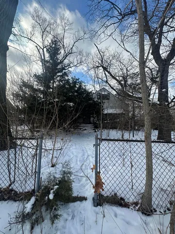 a side view of a yard with wooden fence and trees