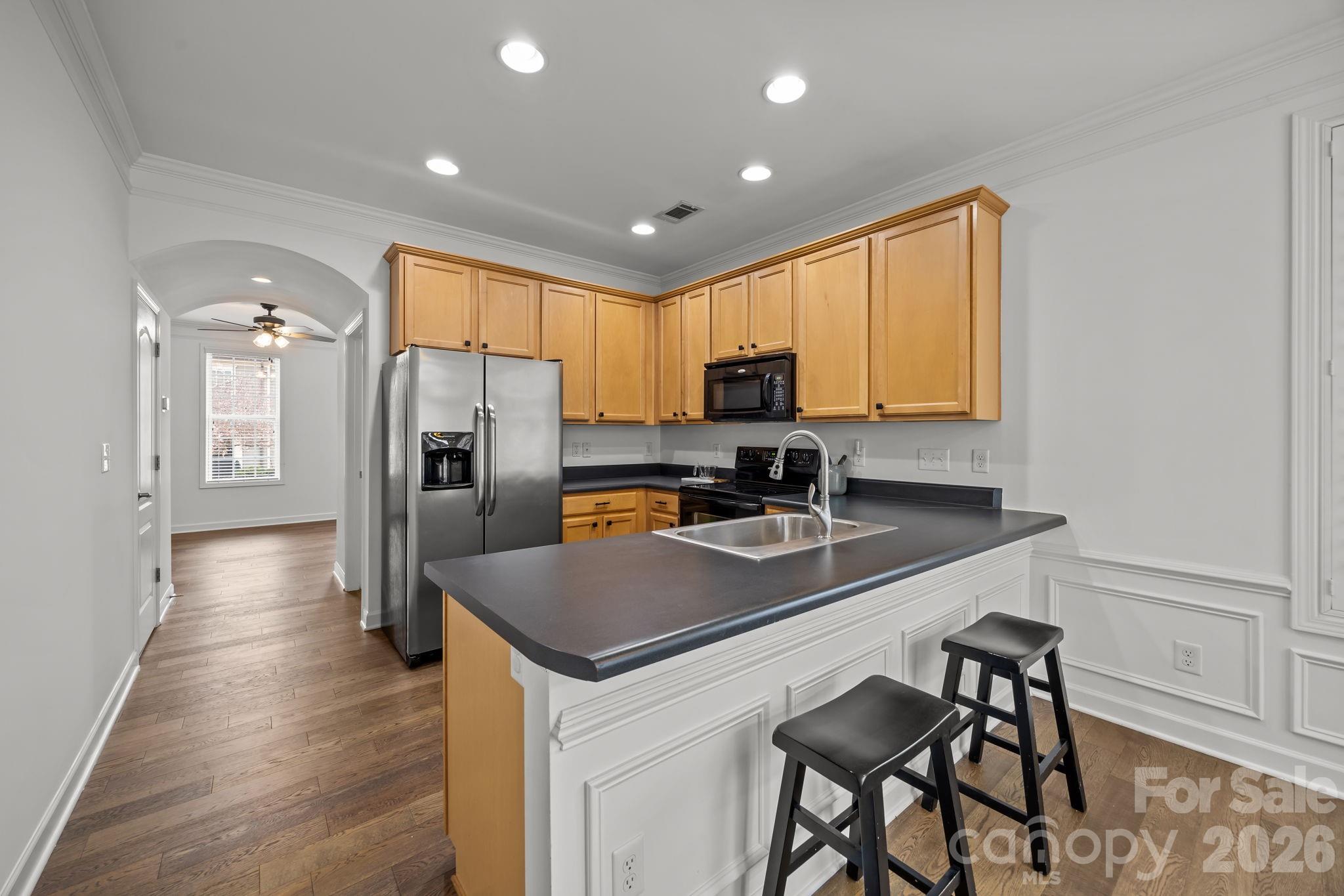 11422 Potters Row Cornelius, NC 28031 - Photo 15 of 46 a kitchen with stainless steel appliances granite countertop a refrigerator a sink dishwasher a stove a dining table and chairs with wooden floor