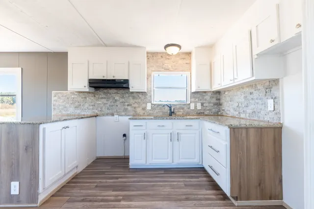 a kitchen with granite countertop cabinets stainless steel appliances a sink and a window