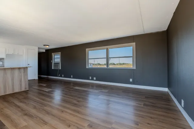 a view of an empty room with window and wooden floor