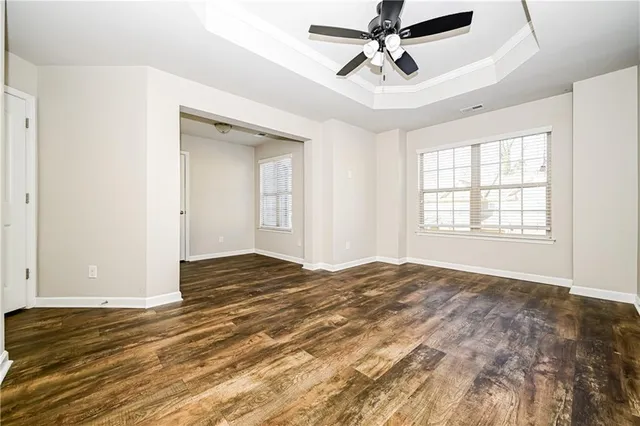 a view of empty room with wooden floor and fan