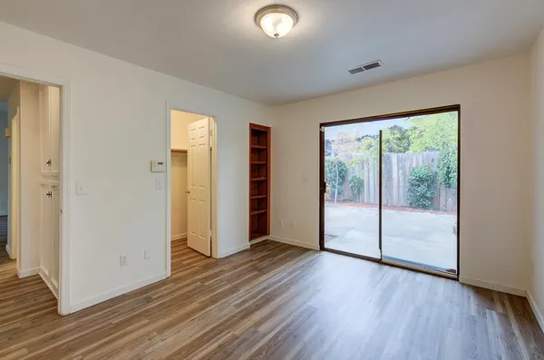 a view of an empty room with wooden floor and a window