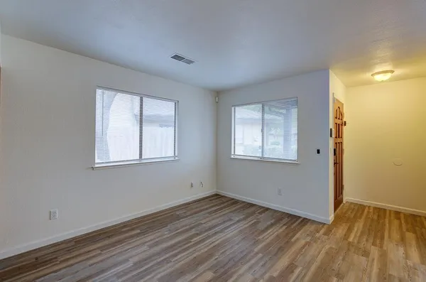 a view of an empty room with wooden floor and closet