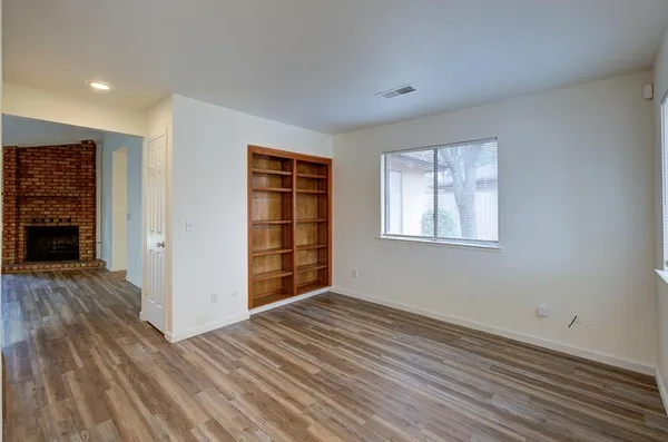 a view of an empty room with wooden floor and a window
