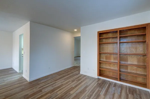 an empty room with wooden floor fireplace and windows