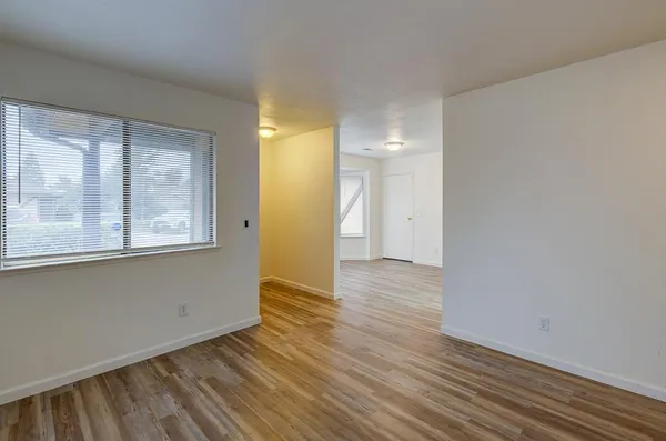 a view of an empty room with wooden floor fireplace and a window