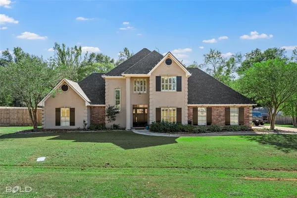a front view of a house with a yard and green space