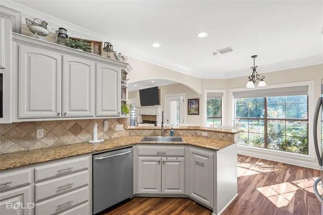 a kitchen with granite countertop kitchen island stainless steel appliances a sink stove and cabinets