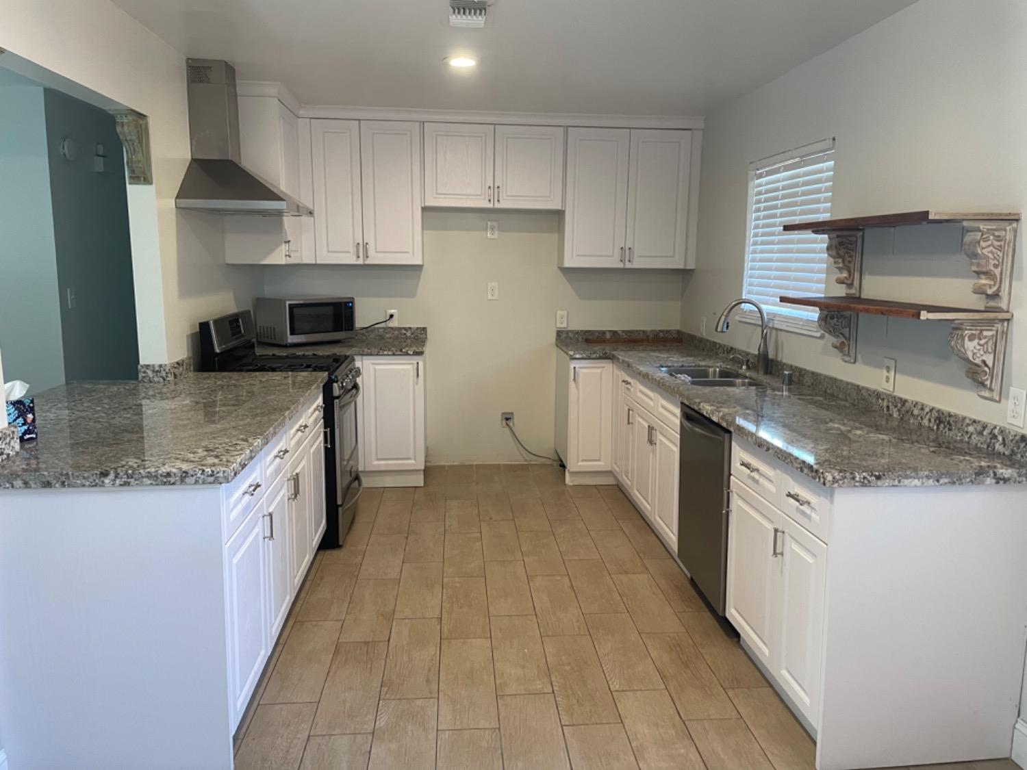 917 Davis Street Madera, CA 93638 - Photo 3 of 10 a kitchen with stainless steel appliances granite countertop a sink stove and refrigerator