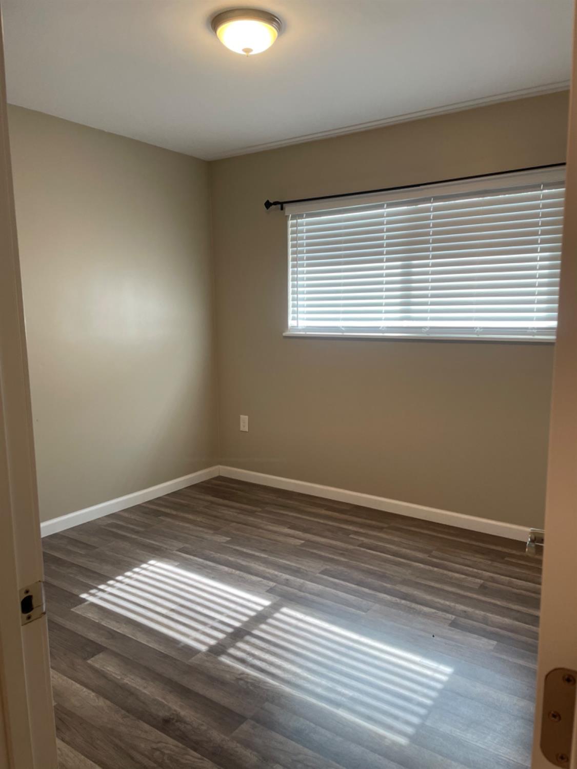 917 Davis Street Madera, CA 93638 - Photo 9 of 10 a view of an empty room with wooden floor and a window