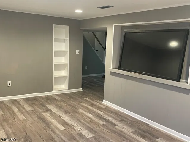 a view of an empty room with wooden floor and closet