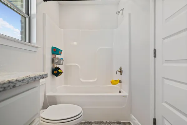 a bathroom with a granite countertop toilet and a bathtub