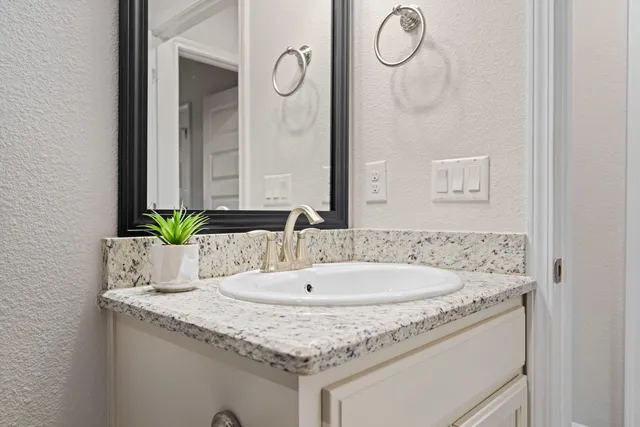 a bathroom with a granite countertop sink and a mirror